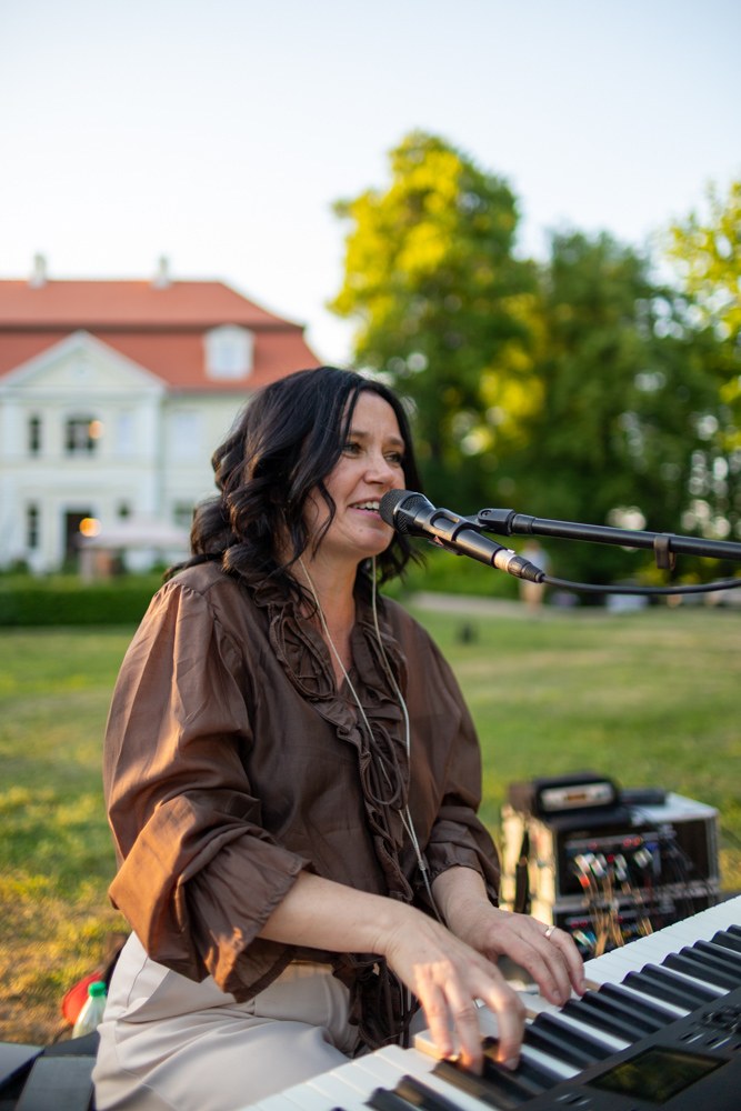Karolina Tuz śpiewa przy instrumencie klawiszowym podczas koncertu w plenerze